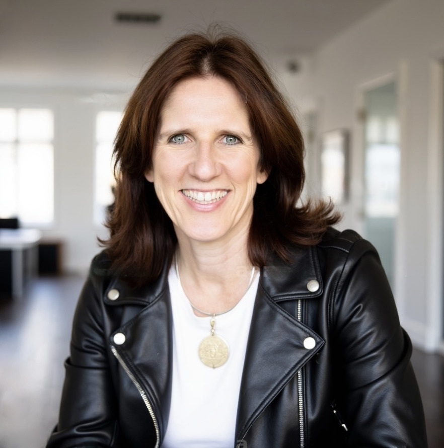 Claudia Beck, MCC, executive coach and founder of Better Together Group, smiling in a black leather jacket