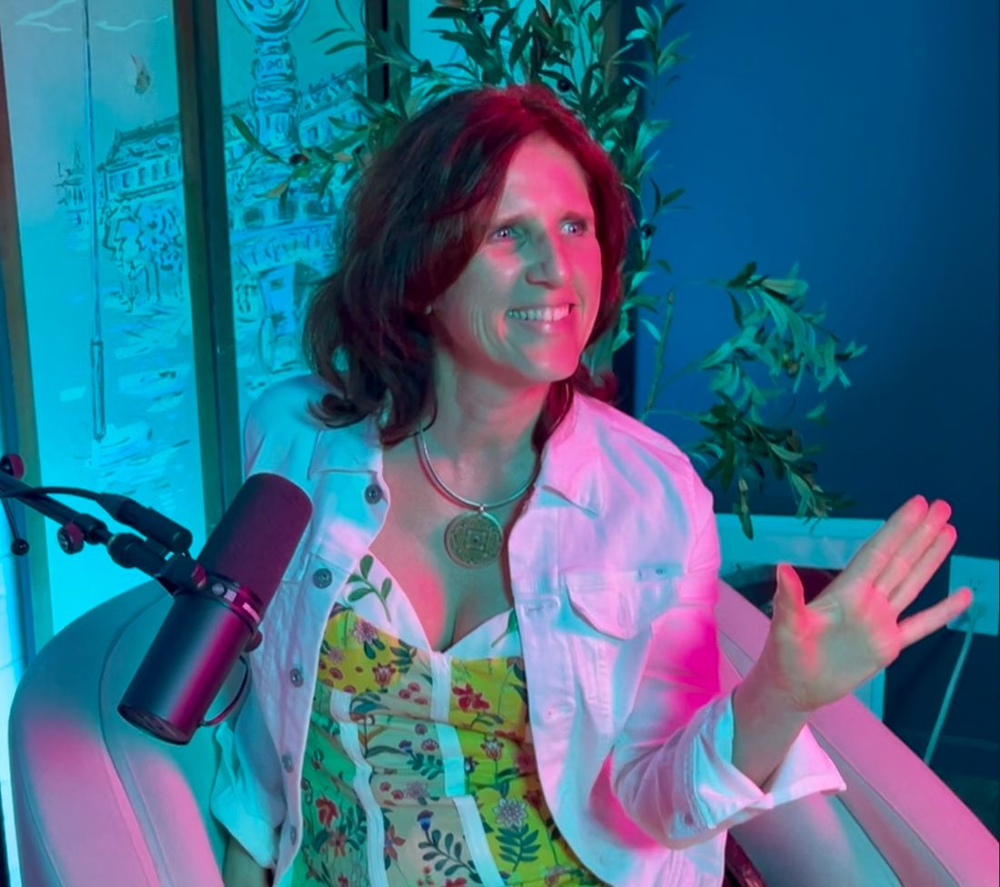 Claudia mid-conversation at a podcast microphone