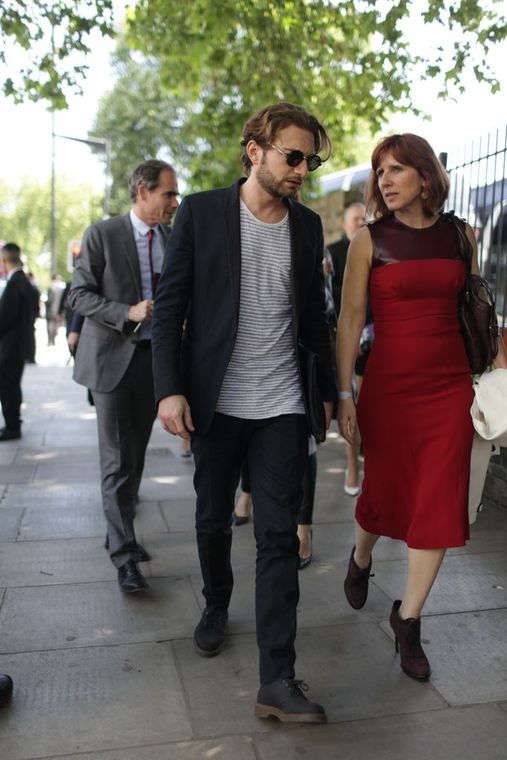 Street photo of Claudia in a red dress, walking with two men